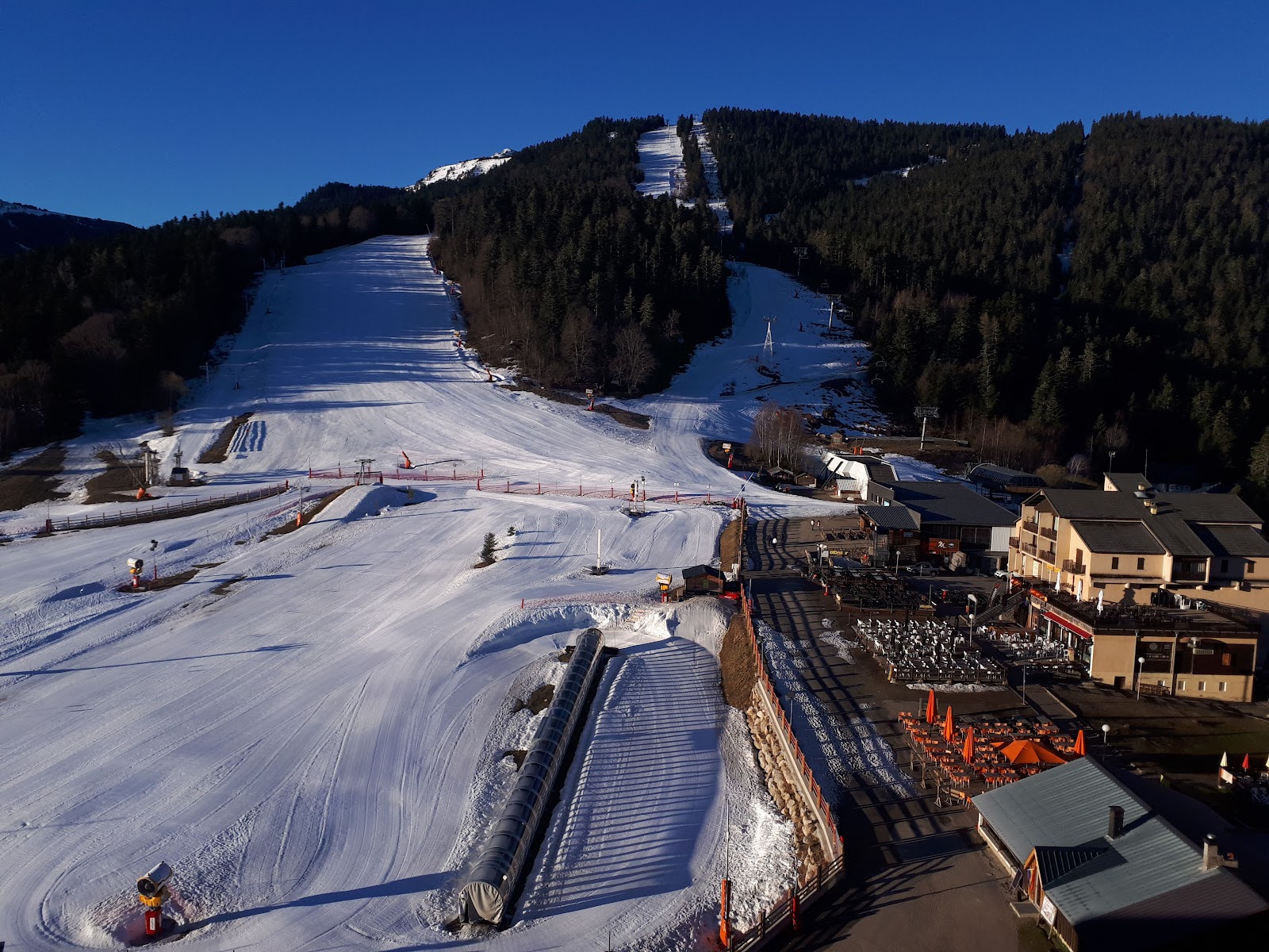 Skiers on a wide sunny blue piste in the Saquet sector of Ax 3 Domaines