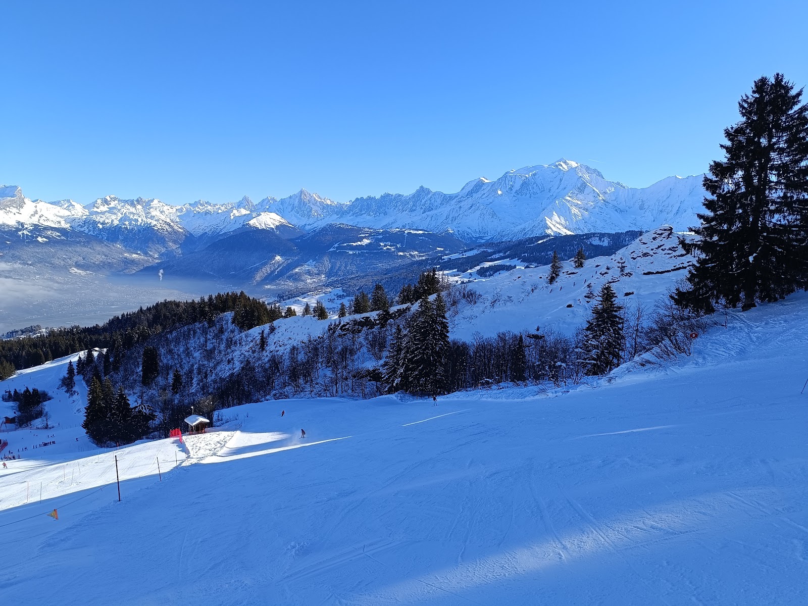 A gentle groomed piste above Combloux with the Mont Blanc massif behind