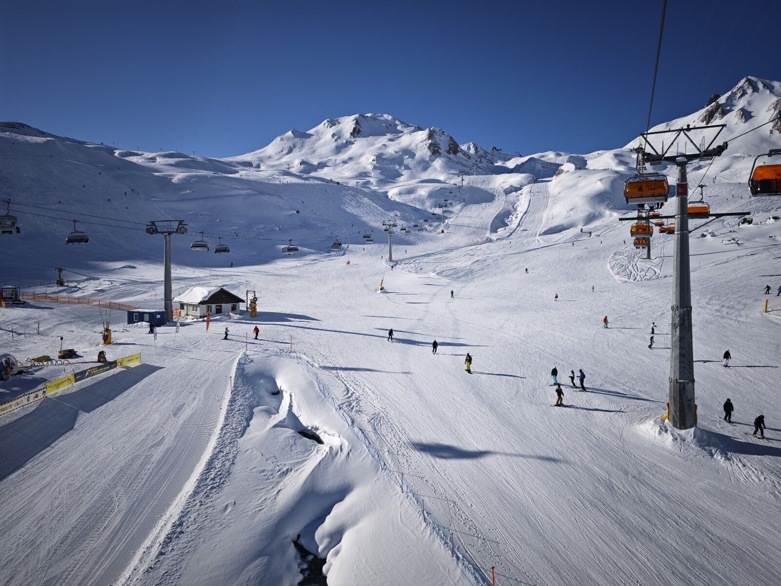 Skiers on a wide well groomed red piste in the Silvretta Arena