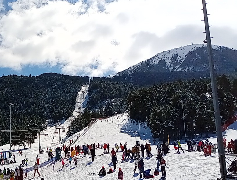 Skiers cruising a wide blue run under blue Spanish skies