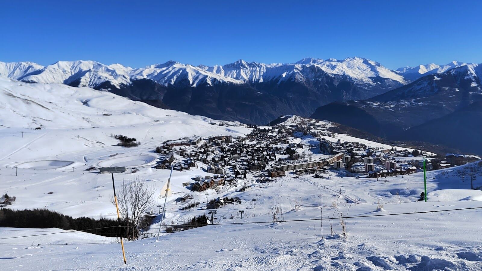 The open plateau village of La Toussuire under snow with the Sybelles ridgelines behind