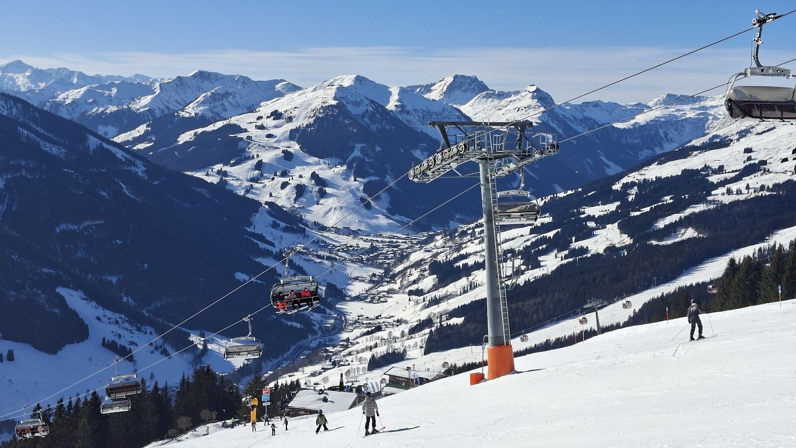 Skiers on a groomed red run above Leogang in the Skicircus