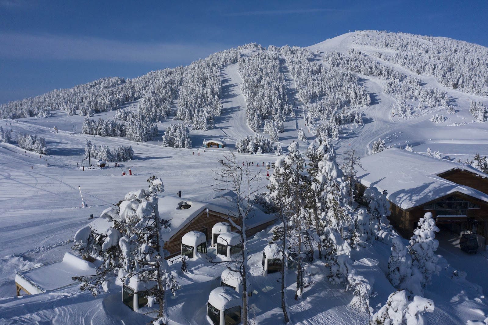 Skiers on a wide groomed run with views over the Capcir plateau