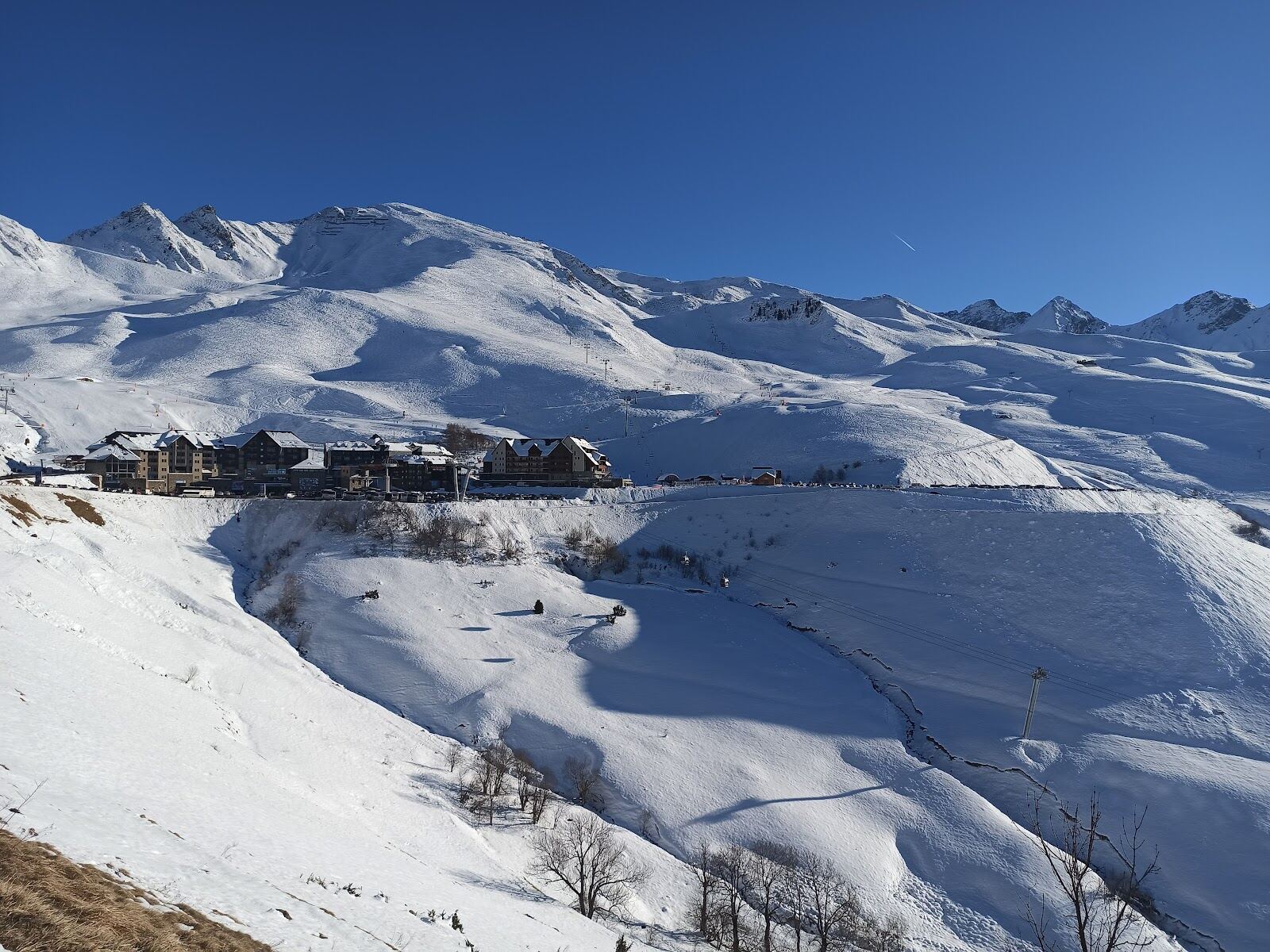 Skiers descending a wide sunny run in the French Pyrenees