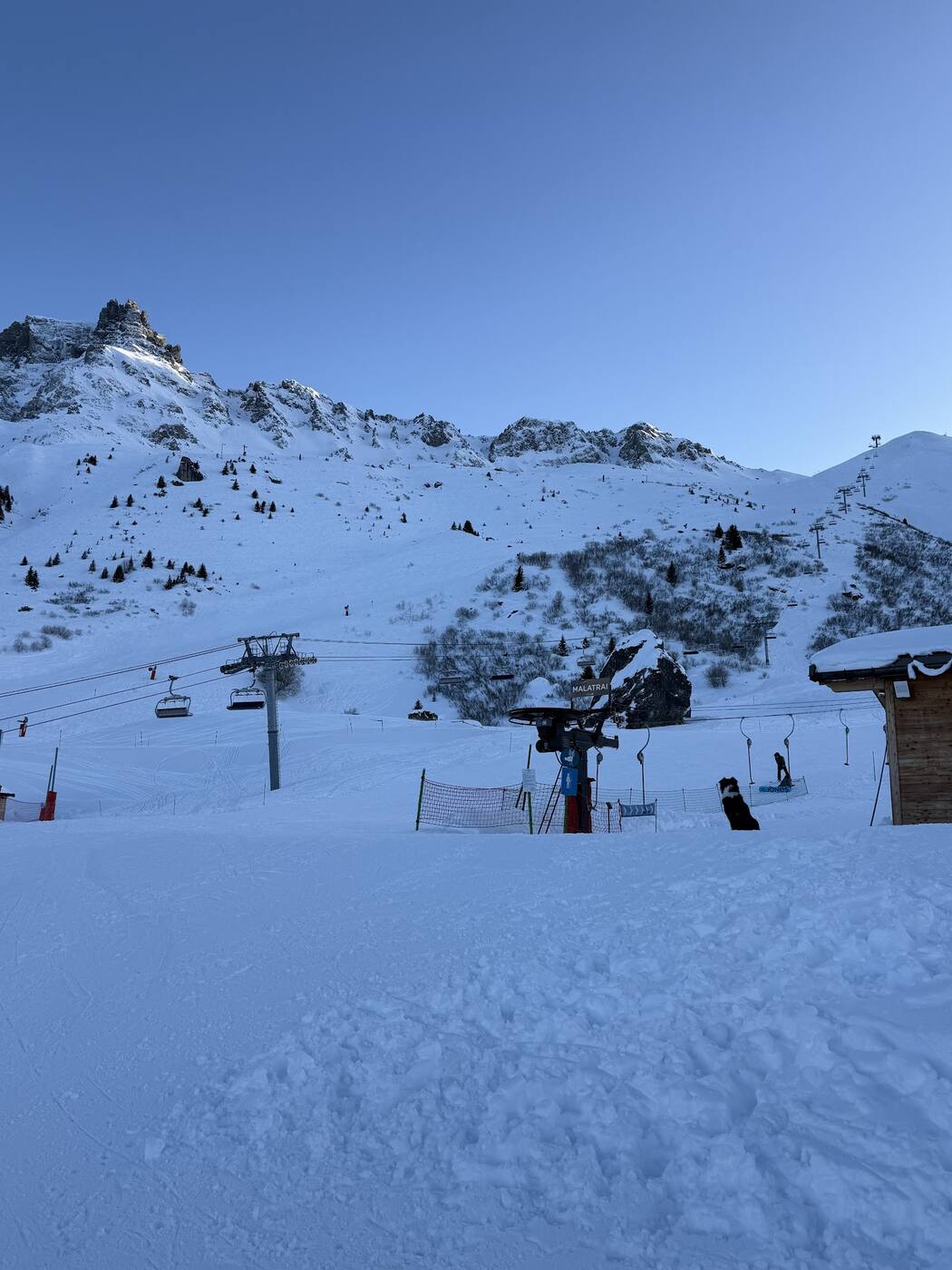 Wooden chalets of the hameaux scattered through snowy trees below the slopes
